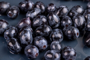 a beautiful blue grape, torn from a branch, lying on a bowl, covered with drops of water, wet fruits of pure blue grapes on a blue bowl during cooking