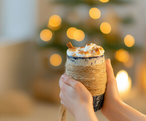 Hands Holding Cozy Mug of Hot Chocolate with Toasted Marshmallows and Cinnamon Stick