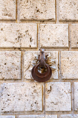 Rusty Iron Door Knocker on Weathered Stone Wall Creates Vintage Historic Exterior Look