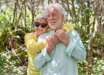 Happy active senior couple enjoying mountain hike day in the forest appreciating nature and freedom, retired seniors hugging expressing love and care