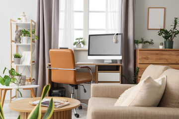 Interior of living room with workplace, sofa and green plants