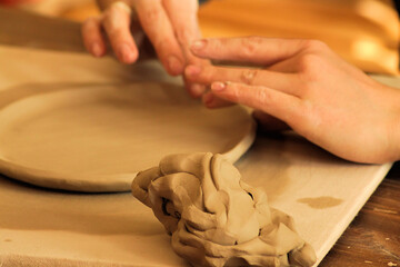 Beautiful female hands working on clay plate in pottery workshop. Sculpting. Handicraft. Soft clay. Clay products.