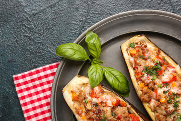Plate with stuffed eggplants and basil leaves on green grunge background