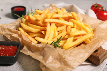 Tasty french fries with rosemary and bowl of ketchup on grey background