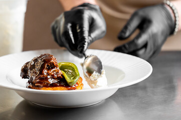 Chef plating gourmet meal in professional kitchen