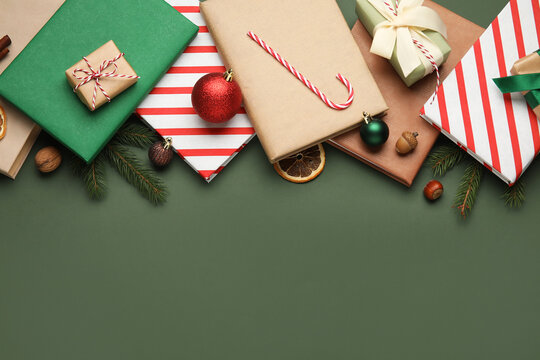 Books with Christmas balls, candy cane, gift boxes and fir branches on green background