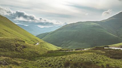 Scenic view of lush green mountains and a winding road under a cloudy sky