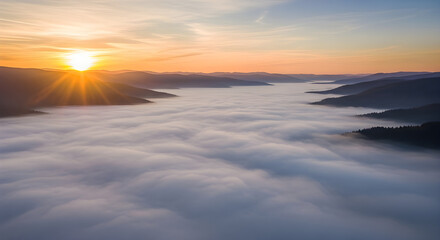 Sunrise over a misty valley with sunbeams breaking through clouds