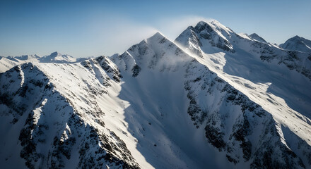 Majestic snow capped mountain peaks bathed in sunlight under a clear blue sky