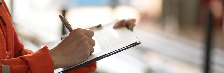 Close-up at supervisor hand is using pen to checking on project risk assessment form to evaluate serverity level. Industrial or business working scene. 
