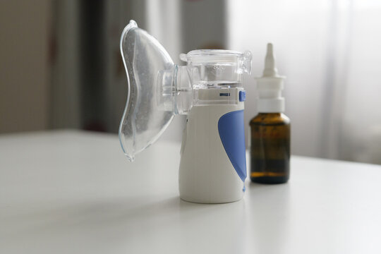 A nebulizer sits on a clean table beside a bottle of medication, illuminated by natural light from a nearby window in a cozy space