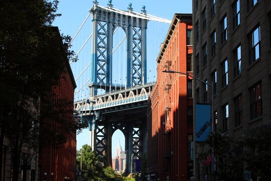 iconic view of manhattan bridge tower seen from the dumbo area in brooklyn with the empire state building in background