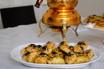 Tea brewing in a traditional Turkish handmade copper teapot. Pastries, desserts, börek, and salads. Iftar table. Breakfast table. Turkish handmade copper teapot set. Pink napkin holder.