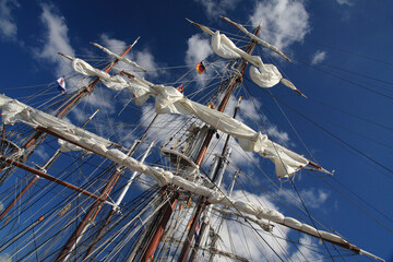 Tall ship masts and sails against blue sky