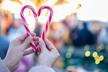 A girl makes a heart out of Santa Claus candies with her hands at the Christmas and New Year's fair.
