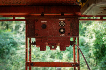 Close-up of the rugged, red communication panel on abandoned mining control equipment, showing connection ports for an operator's headset and microphone