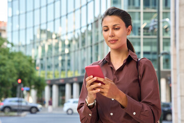 Fototapeta premium Young latin hispanic business woman using smartphone cellphone financial trading app. Indian middle eastern female entrepreneur businesswoman holding mobile cell phone for work outdoors. Copy space