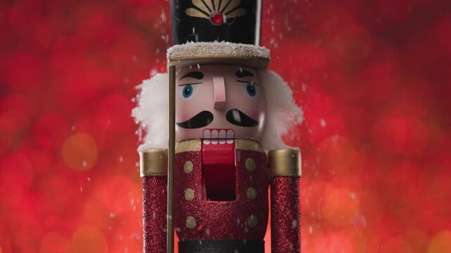 It's snowing on the Nutcracker, closeup framing it's face, on bright red and orange bokeh background