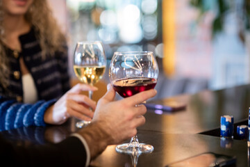  romantic couple toasts with wine glasses at a dimly lit bar or restaurant. 