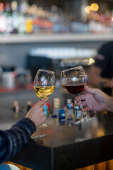  romantic couple toasts with wine glasses at a dimly lit bar or restaurant. 