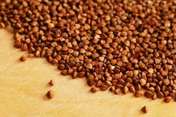 Poured raw buckwheat groats on a wooden kitchen surface.