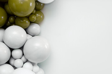 Minimalist balloon backdrop with white and olive-green balloons clustered on the left side, creating a modern festive composition with clean negative space on the right.