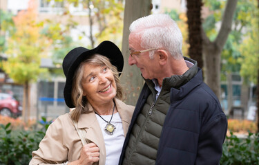 Senior couple looking at each other, smiling, and sharing a moment together outdoors