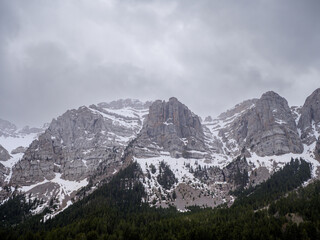 Rugged snow-capped peaks of Sierra del Cadi under gray sky