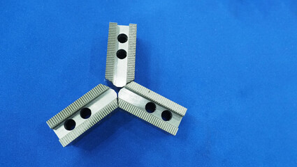 Three precision machined metal jaws on a blue background