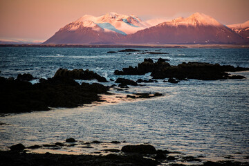 Snowy Mountains and Rocky Coastline at Sunset