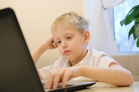 Young boy feeling bored learning online with laptop