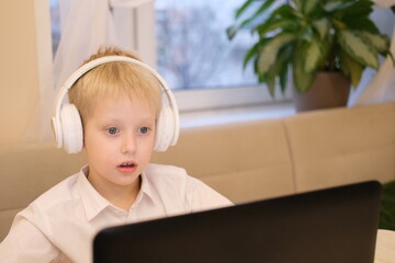 Boy learning online wearing headphones using laptop