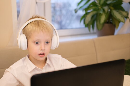 Boy learning online wearing headphones using laptop