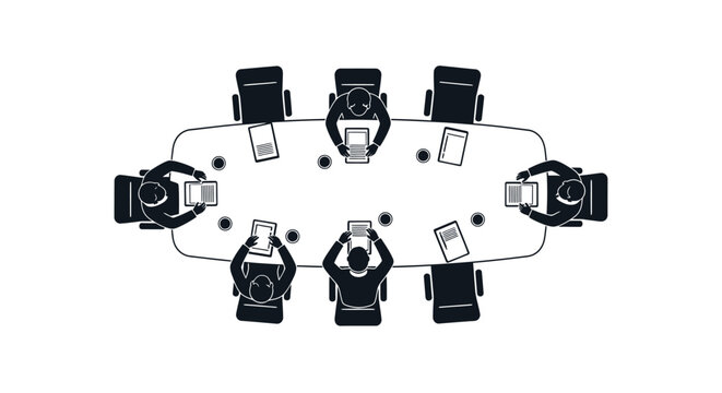 A top down view of people seated around an oval table with laptops