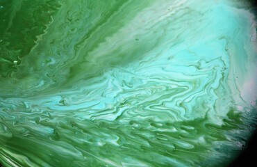 Green abstract background. The acrylic paint flows and creates a unique pattern. The texture of natural stone.