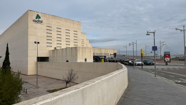 Modern train station under brooding sky, stark concrete lines whisper tales of travelers' journeys, Matariki, Hub City ambience, April 5, 2025, Zaragoza, Spain