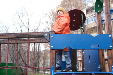 Young boy playing on urban playground in autumn
