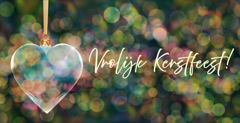 Poczt&oacute;wka bożonarodzeniowa - przezroczysta bombka choinkowa w kształcie serca na tle kolorowych rozmyć świateł bokeh z napisem Merry Christmas w języku niderlandzkim