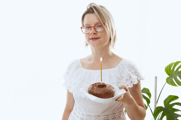 Pretty woman blowing candlelight on a chocolate donut, happy birthday celebration. 