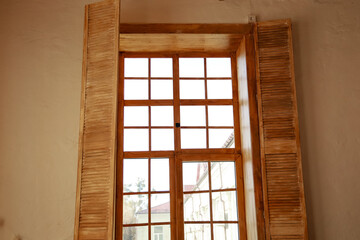 Obraz premium Window with wooden shutters in a bright room showing sunlight on a clear day