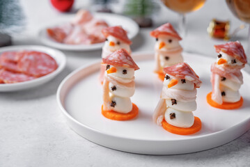 Mozzarella balls with sausage, bacon and carrot slices in the form of snowman for Christmas holidays