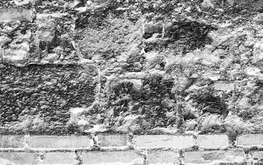 Close up of a weathered brick wall with crumbling mortar in black and white grayscale image style
