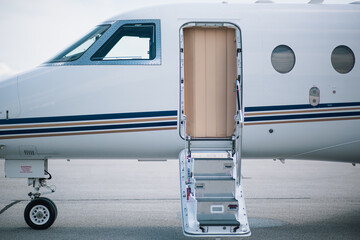 Boarding stairs of a private jet extend to the ground, inviting passengers into the luxury cabin.