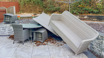 Rattan garden furniture piled up after the impact of very strong winds from a storm. No people.