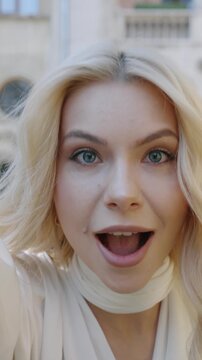 A young woman moves close to the camera, reaching her hand toward the lens before stepping farther away, creating  dynamic shot with natural movement and modern urban energy.
