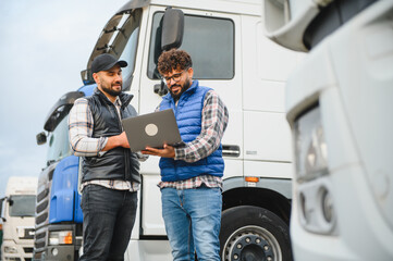 Naklejka premium Truck drivers discussing logistics using laptop at terminal