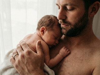 Fototapeta premium Father holding newborn baby skin to skin bonding with copy space