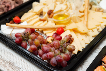 Cheese and fruit platter display. An enticing arrangement of cheese slices, grapes, and nuts on a stylish platter. 