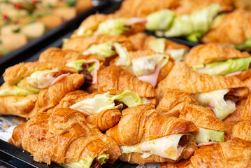 Fresh croissant sandwiches display. Delicious croissant sandwiches filled with fresh ingredients are arranged on a serving tray. 