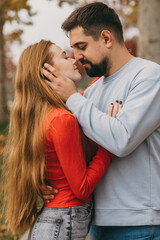 Fototapeta premium couple sharing cozy fall moment, intimate scene with redheaded woman and bearded partner outside